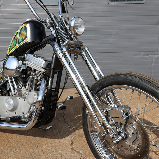 Chrome motorcycle parked on a concrete surface with a gray wall in the background
