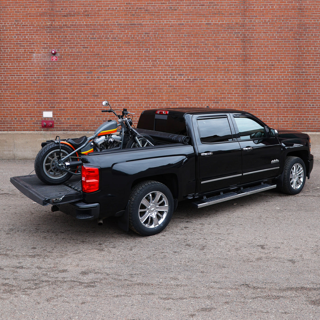 Truck with custom motorcycle in the bed in front of a brick wall