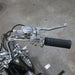 Close-up of motorcycle handlebar with chrome controls on a concrete surface