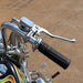 Close-up of a motorcycle handlebar with chrome controls and black grips on a brown background