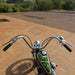 Motorcycle with a colorful fuel tank on a paved road with greenery in the background