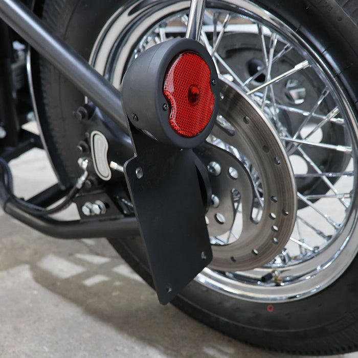 Close-up of a motorcycle's rear wheel with a red reflector attached.