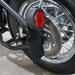 Close-up of a motorcycle's rear wheel with a red reflector attached.