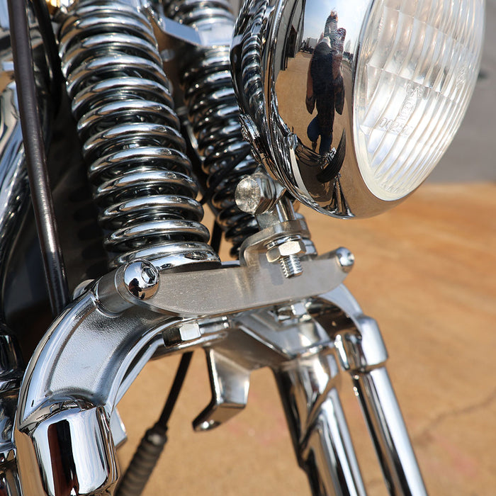 Close-up of a motorcycle's headlight and suspension system with a blurred background.