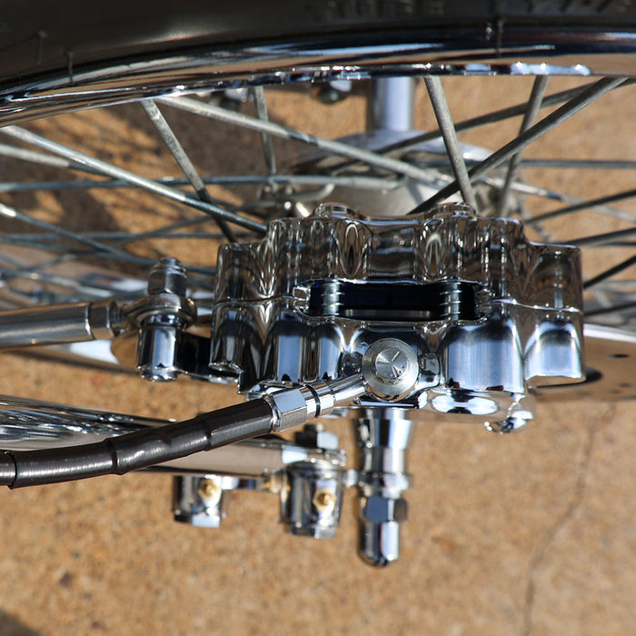 Close-up of a motorcycle's rear wheel and suspension system on a textured surface.