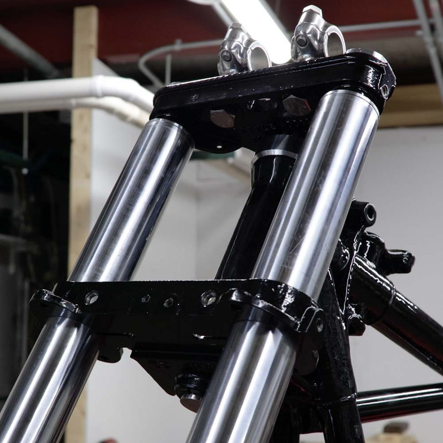 Close-up of a motorcycle's front suspension system with a blurred background.