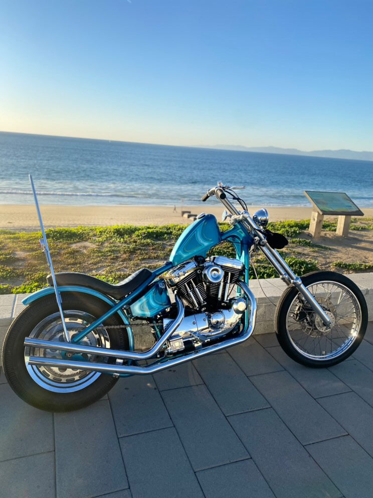 Blue sportster chopper with ocean in background