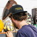 Person wearing a cap with 'Throttle Addiction' text, standing in front of a dartboard.