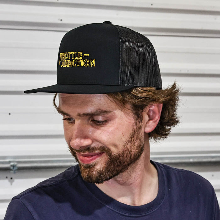 Man wearing a black cap with 'Prostitute Addiction' text against a metallic background