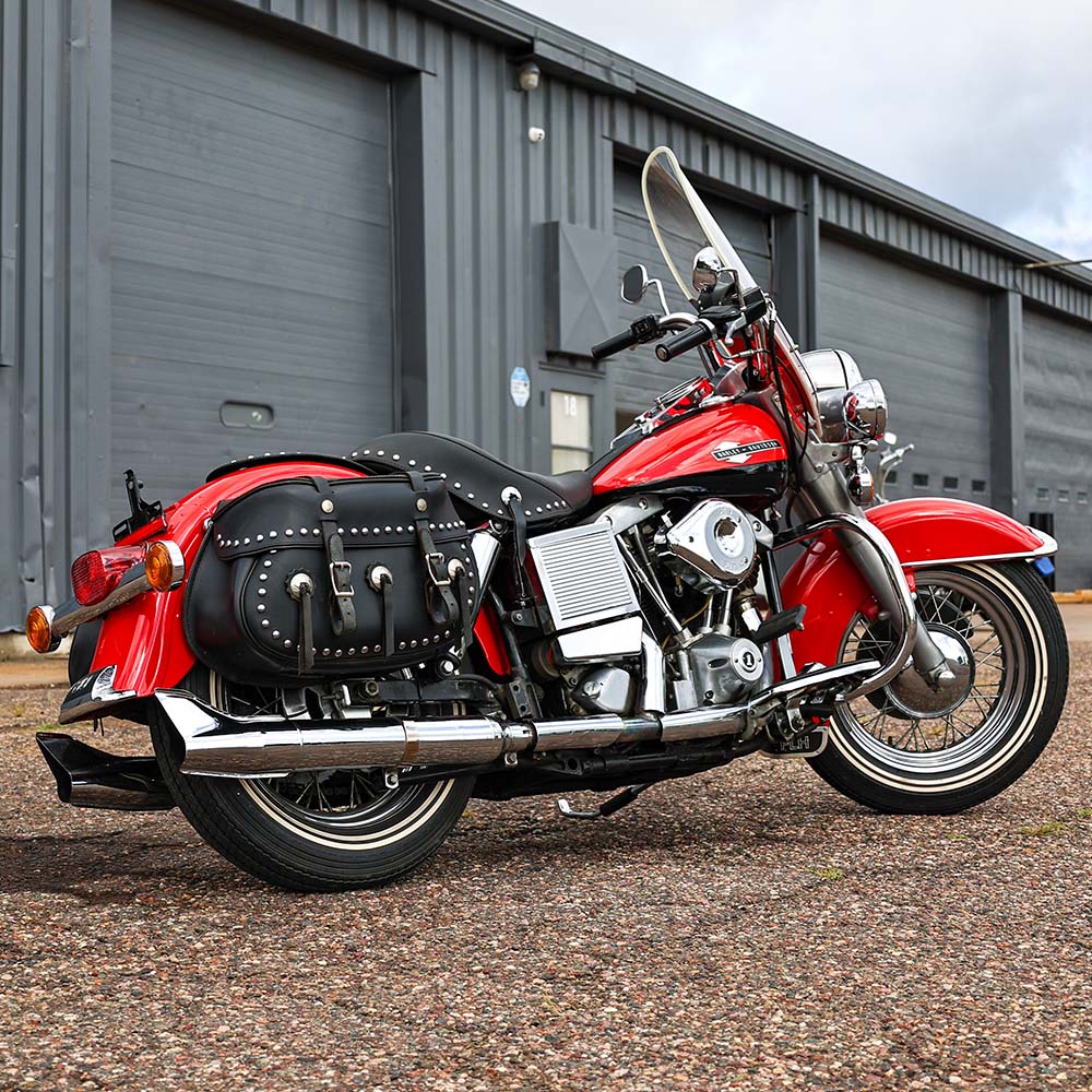 Red motorcycle with black saddlebag parked in front of a building