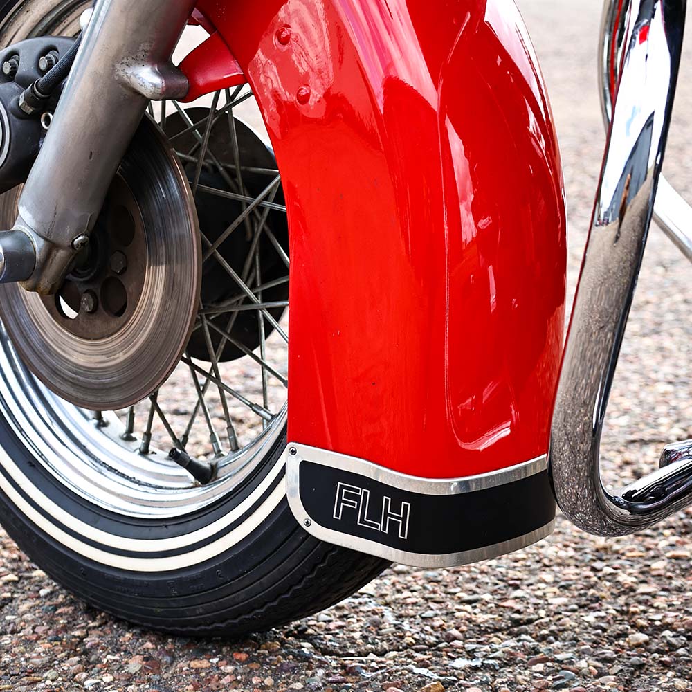 Close-up of a red motorcycle with 'FLH' branding on a textured surface