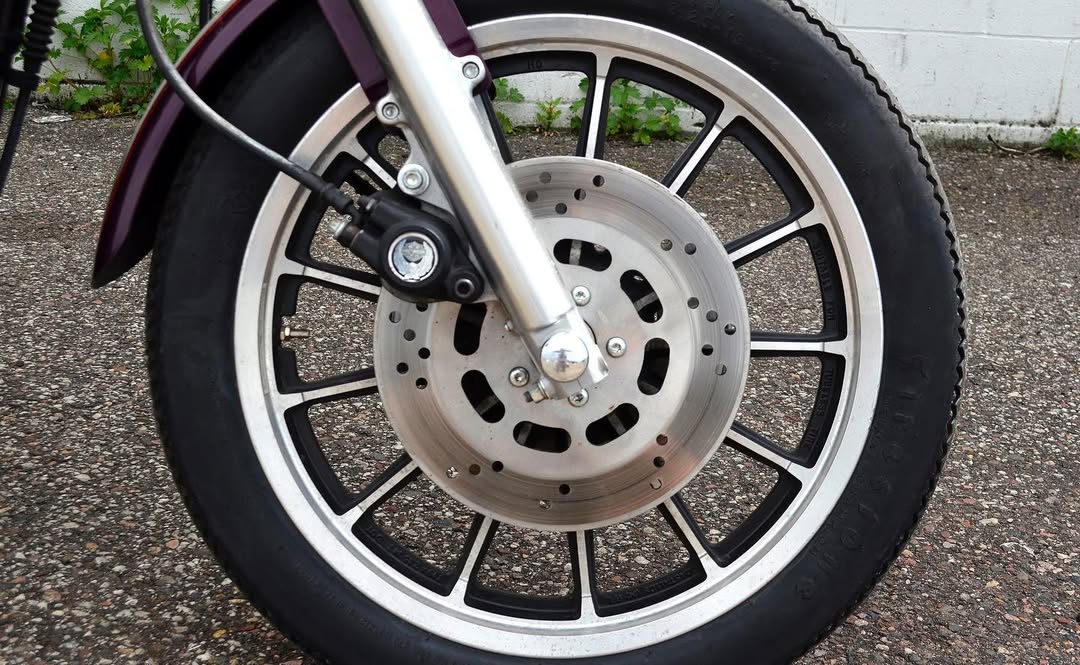 Close-up of a motorcycle wheel with disc brake on a road.