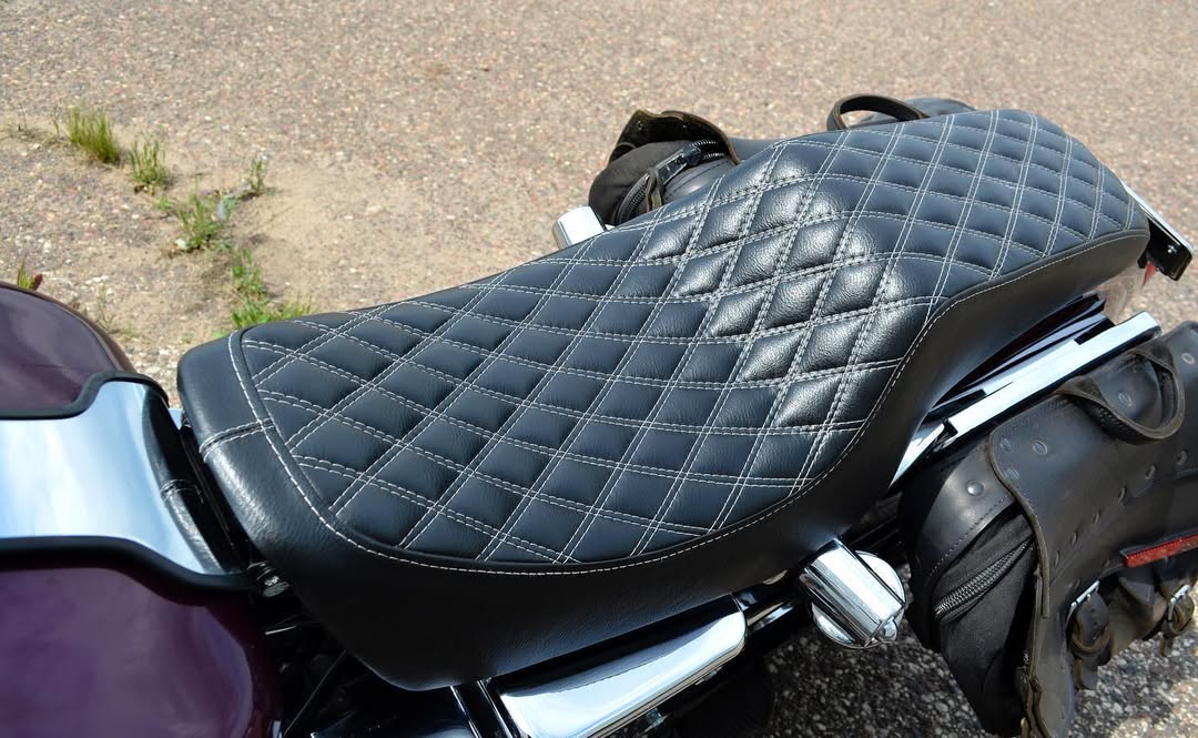 Close-up of a motorcycle seat with quilted design on a road.