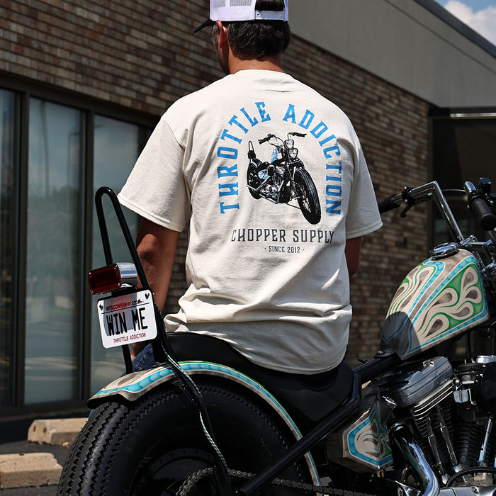 Person wearing a 'Throttle Addiction Chopper Supply' t-shirt sitting on a motorcycle.
