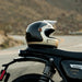 Champagne and charcoal helmet on a motorcycle with a blurred road and mountains in the background