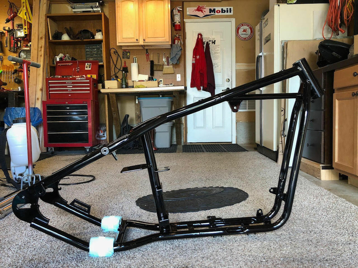 painted hardtailed sportster frame in a garage